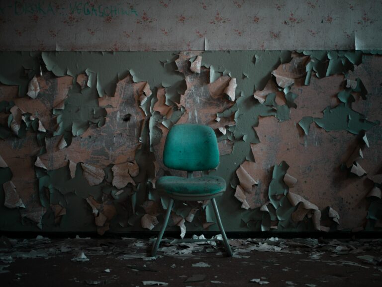 pain and suffering: peeling wall with a green chair infront of the wall